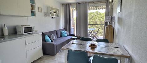 A compact living space with a kitchenette, a dining area, and a sofa.