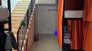 Une chambre de dortoir avec des lits superposés, un escalier et une petite fenêtre.