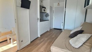 Een knusse kamer met een bed, een bureau en een kitchenette.