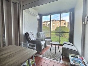 A balcony with wicker furniture, a table, and a magazine rack. - T2 en Rez de jardin plage de Miramar (La Londe-les-Maures)