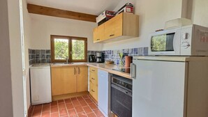 Una cucina funzionale con mobili in legno, un frigorifero bianco, un forno a microonde e una macchina da caffè.