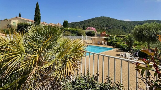 Area piscina con vista chiara su una montagna sullo sfondo, circondata da vegetazione e una recinzione.