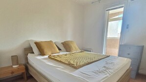 A bedroom with a bed, two pillows, a bedside table, and a nightstand. - Joli Mazet T3 avec piscine (La Londe-les-Maures)
