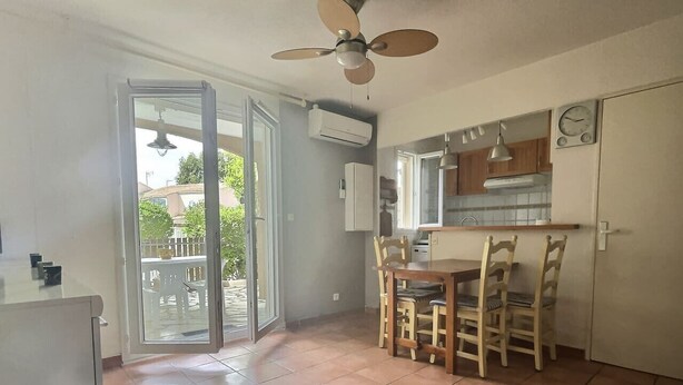 A kitchen with a dining area, a ceiling fan, and an air conditioning unit. - Joli Mazet T3 avec piscine (La Londe-les-Maures)
