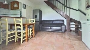 A living room with a dining table, chairs, a sofa, a ceiling fan, a staircase, and a refrigerator. - Joli Mazet T3 avec piscine (La Londe-les-Maures)