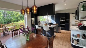 A modern kitchen with dark cabinets, a central island, and pendant lighting. - HATHERLOW - Idyllic Private Retreat in Charming Wedmore (Wedmore)