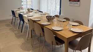 Un espace repas avec une longue table en bois, dressée pour six personnes, entourée de chaises.