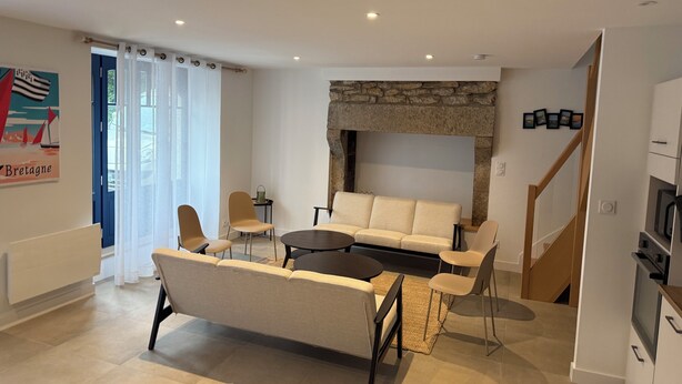 Un salon moderne comprenant un canapé, des fauteuils, une table basse et une cheminée en pierre.