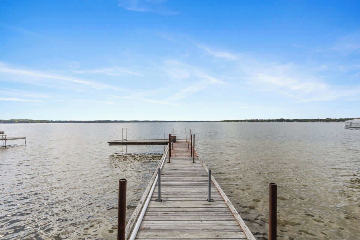 Eine hölzerne Pier, die sich in ruhiges Wasser erstreckt, mit wolkenlosem Himmel darüber.