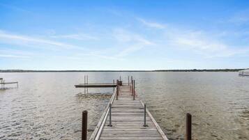 Eine hölzerne Pier, die sich in ruhiges Wasser erstreckt, mit wolkenlosem Himmel darüber.