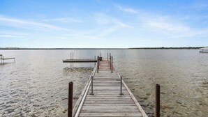 A wooden pier extending into calm water with a clear sky above.