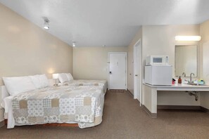 Une chambre d’hôtel équipée d’un lit, d’une lampe de chevet, d’un four à micro-ondes, d’un lavabo et d’un miroir.