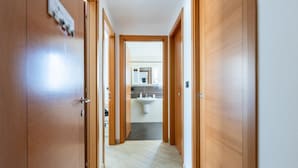 A hallway with wooden doors, a sink, and a mirror in the background. - GuestHost - Cozy 86 sqm apartment, able to comfortably accommodate up to 4 people, located on the third floor of a building with lift.The property, located in a quiet residential area, is about 2 km from Piazza Vittorio Emanuele II and the center of Pisa (Pisa)
