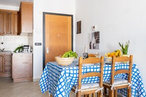 Un comedor con mantel a cuadros, sillas de madera y una puerta con interruptor de luz.