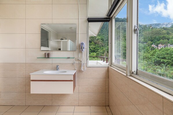 Ein modernes Badezimmer mit großem Fenster, Waschbecken und Spiegel.