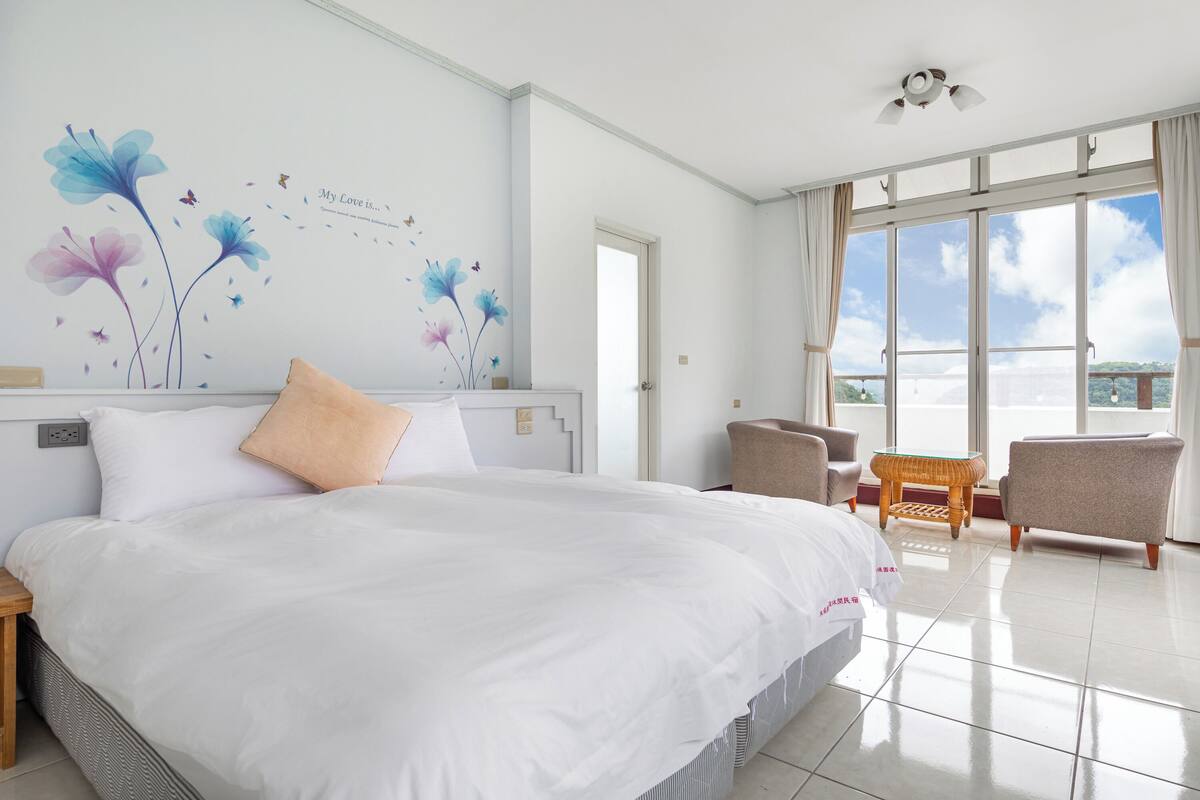 Une chambre d’hôtel avec un grand lit, un bureau, une chaise et une vue sur l’extérieur.