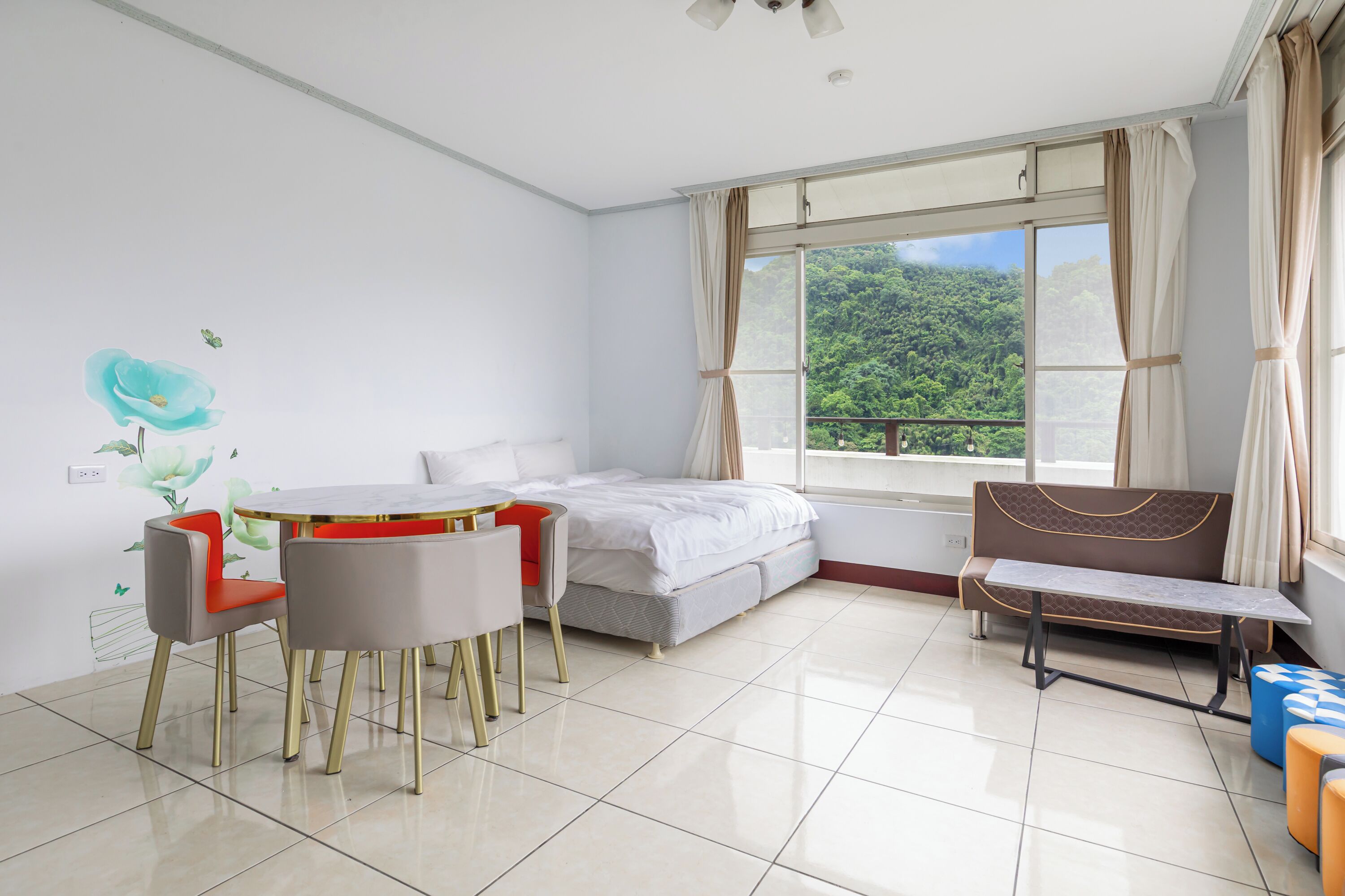 Un dormitorio moderno con cama, una mesa de comedor con sillas, un banco y un ventanal con cortinas.