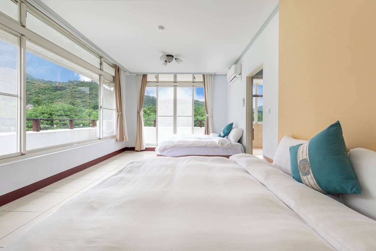 Une chambre d’hôtel dotée d’un grand lit, d’un canapé et offrant une vue sur un paysage montagneux grâce à de grandes fenêtres.