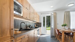 Una cocina moderna con armarios de madera, un microondas Bosch y un comedor con mesa y sillas.