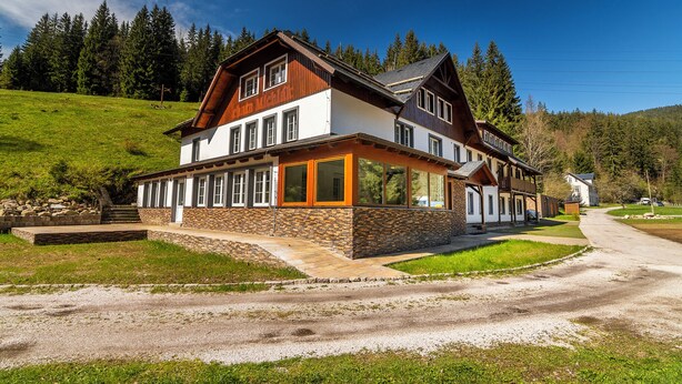 Un chalet de dos plantas con base de piedra, ventanas grandes y fachada de madera.