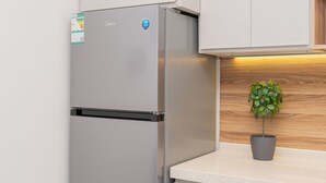 A kitchen with a stainless steel refrigerator, a small potted plant on the counter, and wooden cabinetry. - 118 4A/ Luxury ground floor studio apartment (Riyadh)