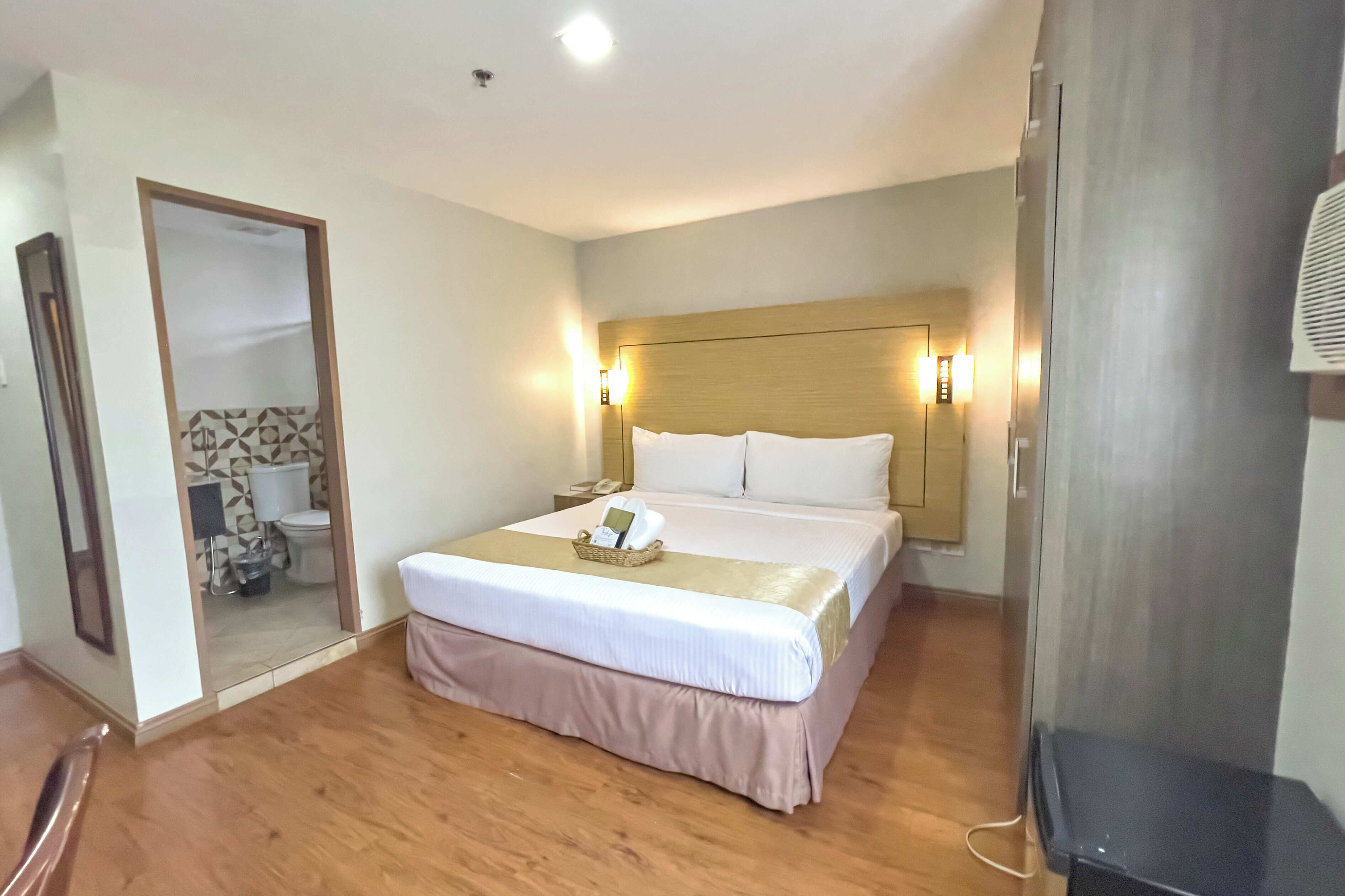 Una habitación de hotel con una cama grande, una mesita de noche y un espejo.