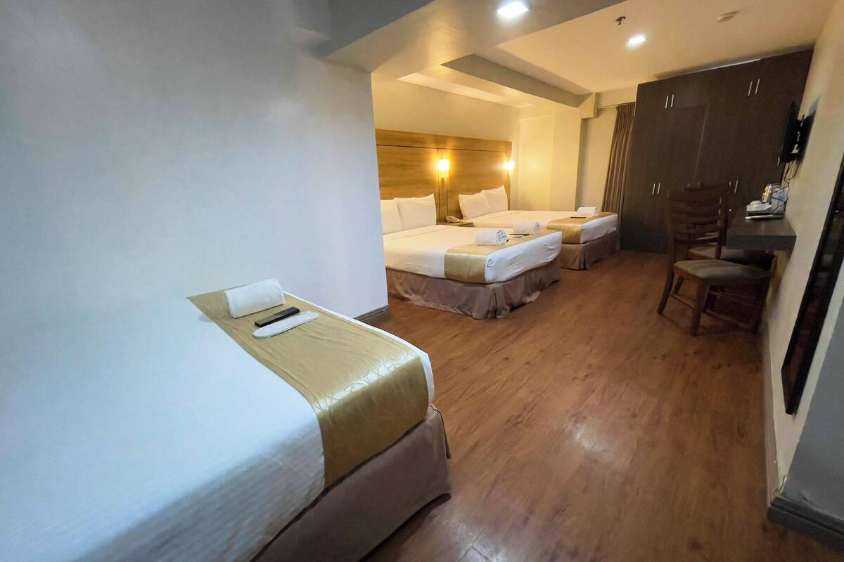 A hotel room with two beds, a desk, and a chair.
