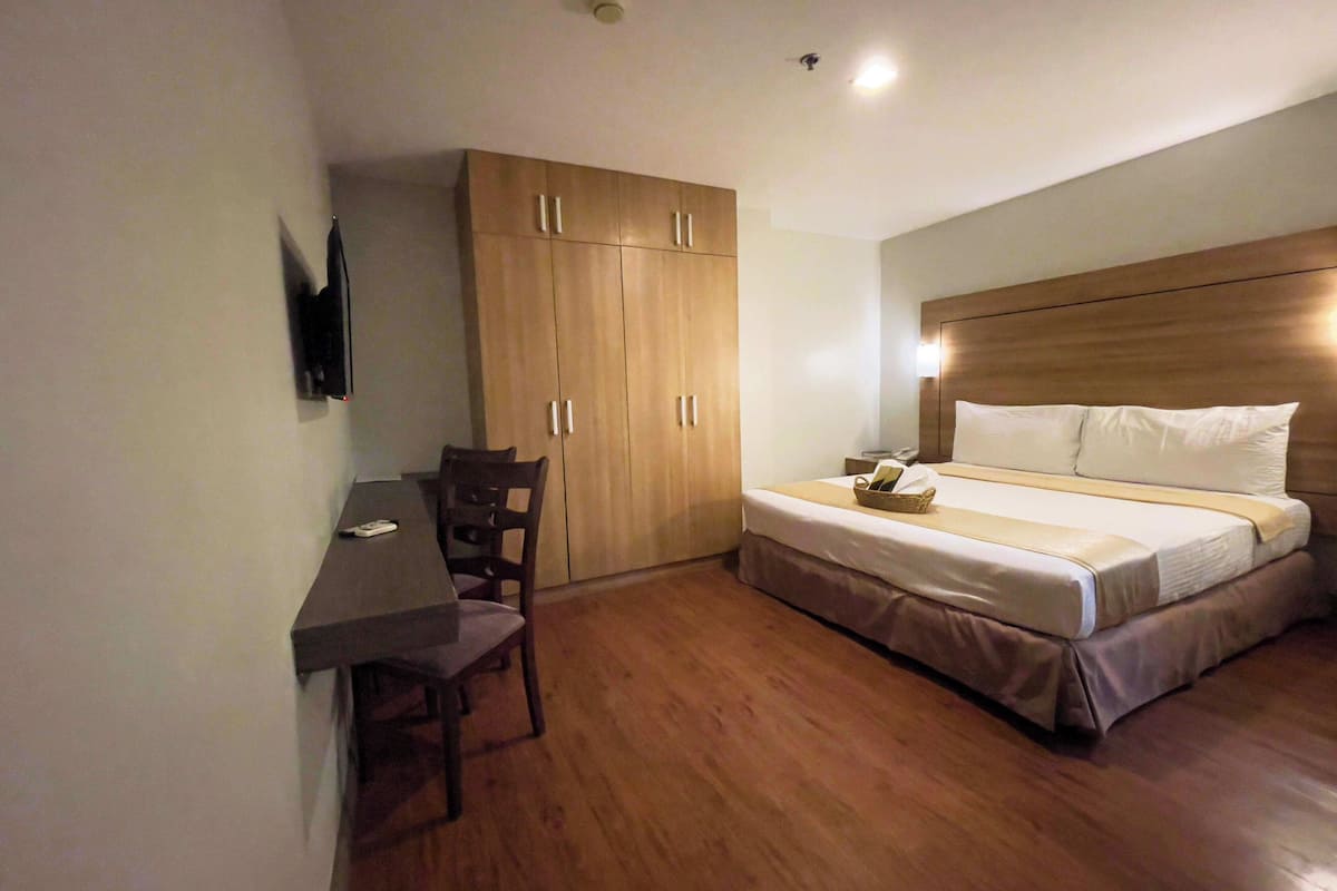 A bedroom with a bed, bedside table, chair, and wardrobe.