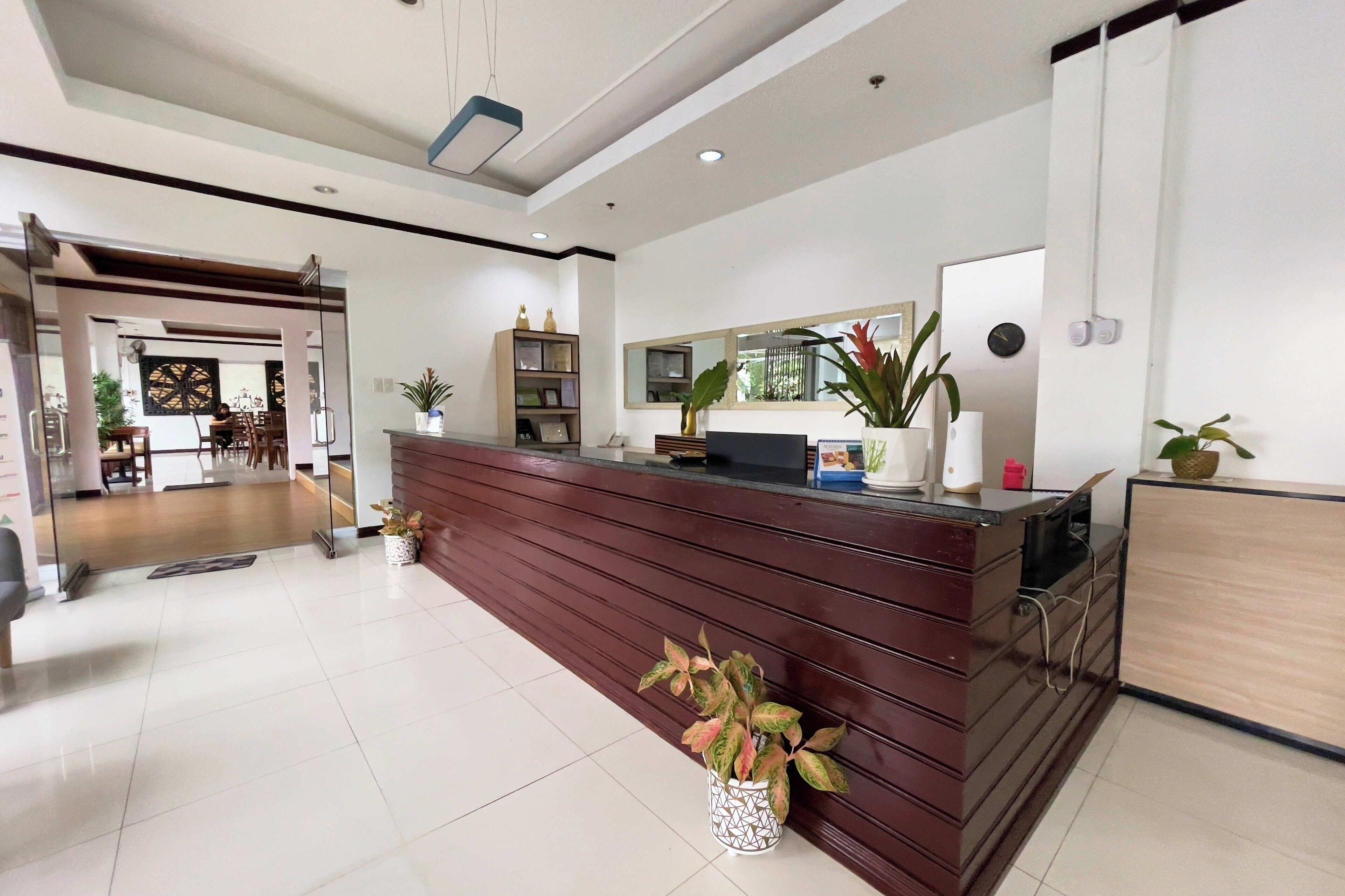 A modern reception area with a wooden reception desk, a large mirror, and potted plants.