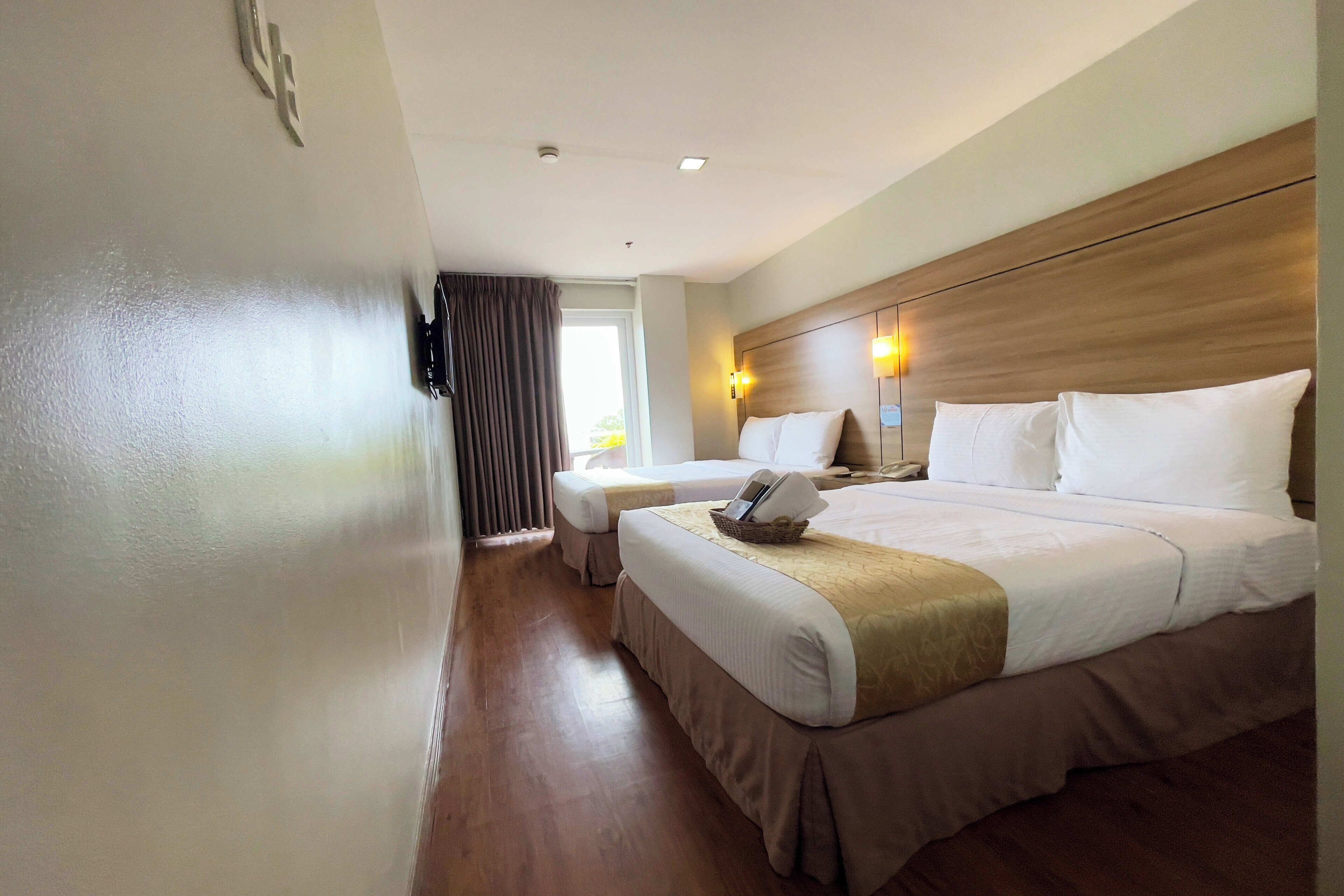 Una habitación de hotel con una cama grande, una cama más pequeña y un escritorio con una silla.