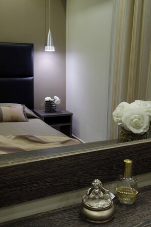 Une chambre d’hôtel bien rangée, avec un lit, une table de chevet et un miroir qui reflète la pièce.