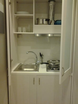 A compact kitchen with a sink, a stove, and a blender on the countertop.