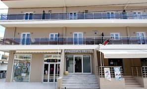 A hotel with a ground floor store named 'BRILLAR' and a second-floor balcony with glass railings.