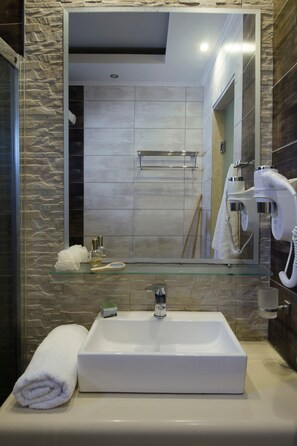 A bathroom with a glass-topped sink, a towel, a mirror, and a hairdryer. - Apartment '207' with Wi-Fi and Air Conditioning (Halkidiki)