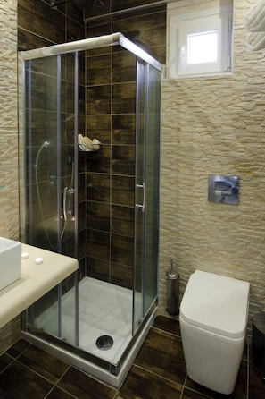 A glass-enclosed shower with a white sink and toilet.