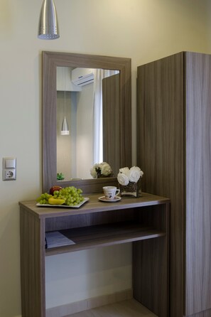 A bathroom vanity with a mirror, a light fixture, a fruit bowl, a cup, and a vase with flowers.