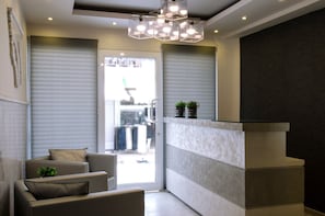 A modern interior with a seating area, a reception desk, and a view through a glass door.