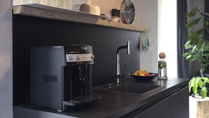 Una cuina moderna amb cafetera, rentapesos i finestra amb vistes.