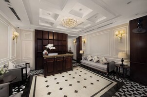 A spacious lobby with a large central area, a sofa, a small table, and a decorative vase.