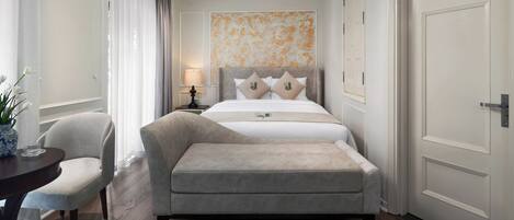 A hotel room with a bed, a chair, a table, and a lamp.