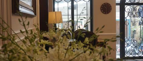 A room with a large window, a lamp, and two wall clocks.