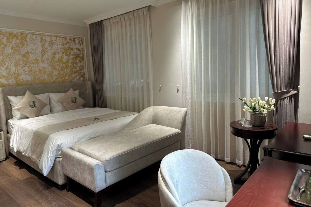 Una habitación de hotel con una cama, un sofá, una mesita con un florero y una silla.