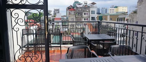 A balcony with outdoor furniture, a metal gate, and a view of the cityscape.