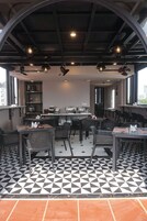A restaurant with a black and white checkered floor, multiple tables and chairs, and a kitchen area in the background.