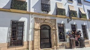 A building with a white facade, multiple windows with black metal grilles, and a central entrance with a stone archway. - Stunning apartment in Ronda with WiFi (Ronda)