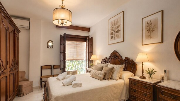 A bedroom with a bed, bedside tables, a wardrobe, and a window with blinds. - Stunning apartment in Ronda with WiFi (Ronda)