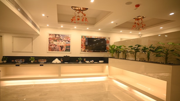 A spacious lobby with a marble floor, a reception desk, wall-mounted televisions, and decorative hanging elements.