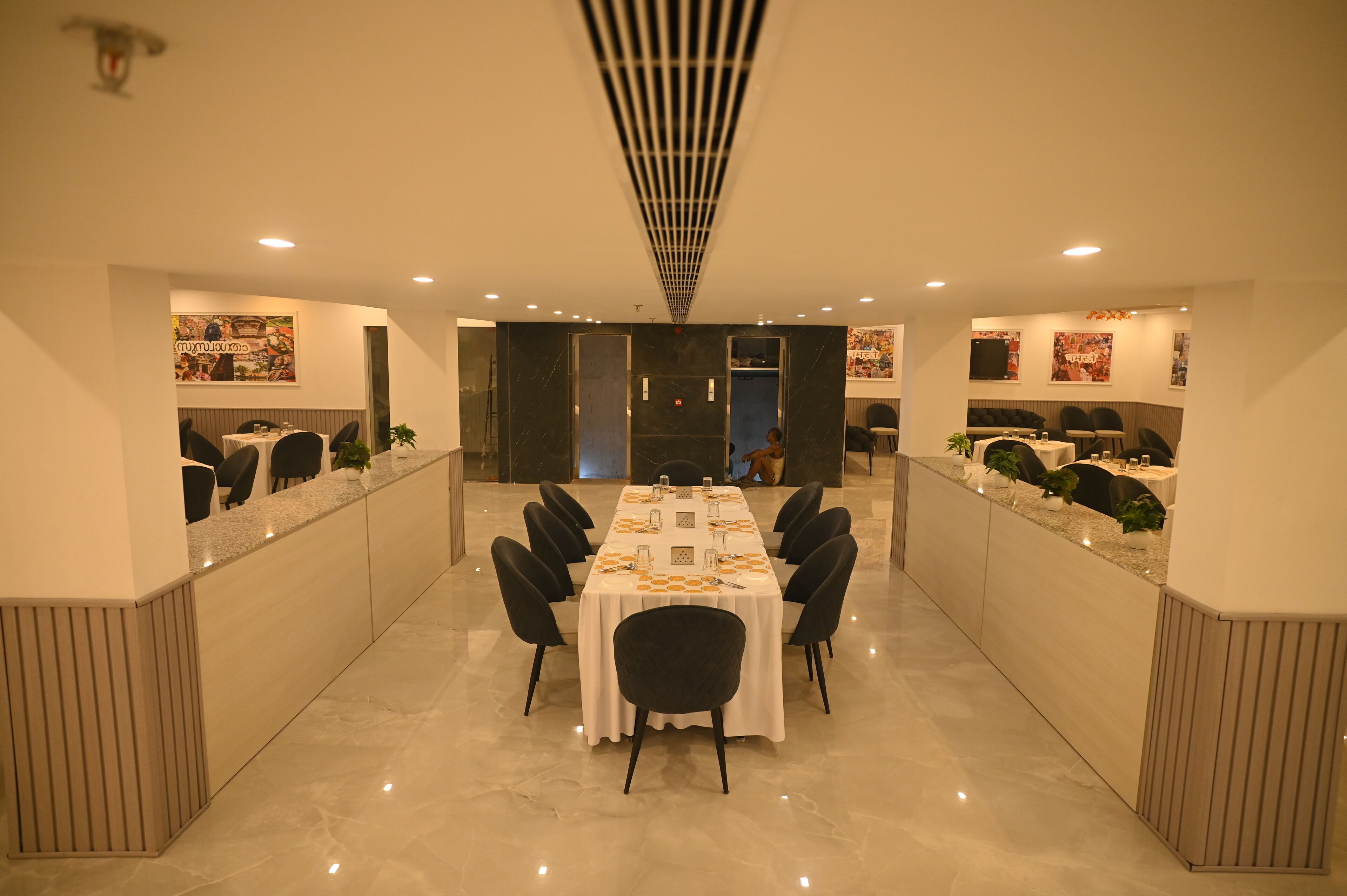 Un salón de conferencias con una larga mesa, sillas negras y un mantel blanco.