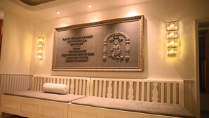 A hotel reception area with a large framed Buddha statue, a white bench with cushions, and wall-mounted lights.