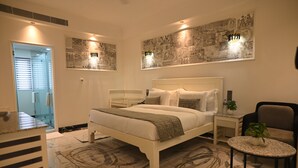 A modern bedroom with a large bed, bedside tables, a small round table, and a chair.